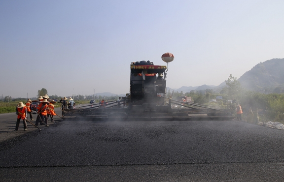 2019年8月，宜春經(jīng)開區(qū)S311路面攤鋪現(xiàn)場，工友們輔助路面兩側(cè)的分料、補窩等作業(yè)