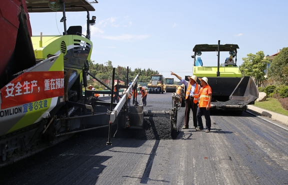 攤鋪機(jī)、壓路機(jī)等設(shè)備緊張有序運(yùn)行，高達(dá)170℃的瀝青混合料炙烤著公路人